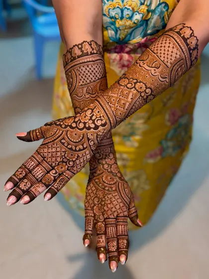 A crossed-hands view of the intricate bridal mehendi.