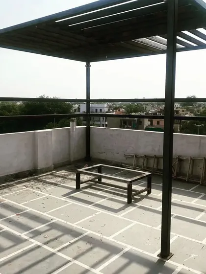A wide shot of the installed pergola on the stone-tiled terrace.