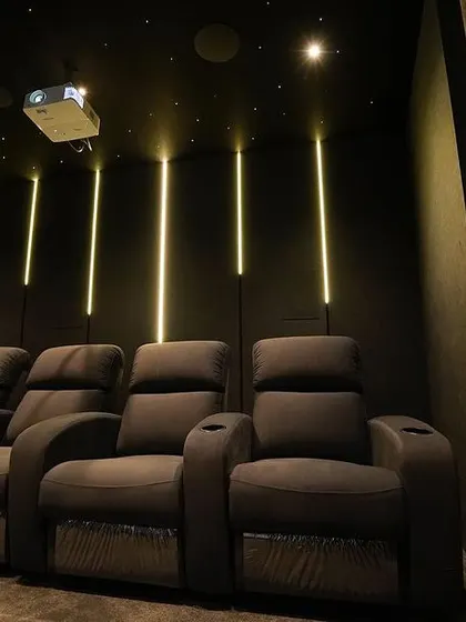 Another perspective of the tiered seating in the Kolapakkam project. The vertical LED lights behind the recliners add depth and a sophisticated glow to the room's modern design.