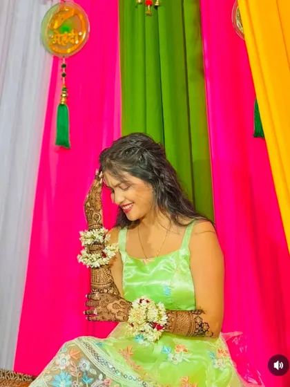 A candid moment of laughter and joy during a mehndi ceremony. The bride looks beautiful with her floral jewelry and detailed henna.