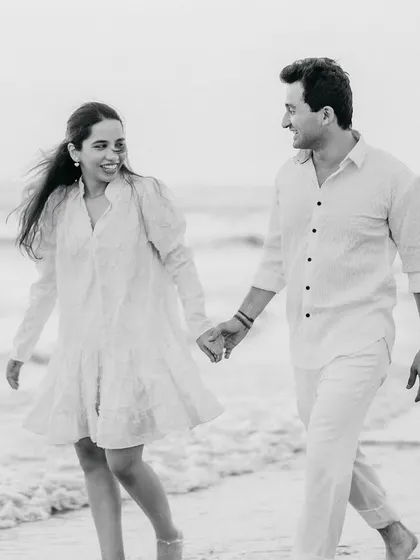 A candid black and white photo of a couple walking and laughing on the beach. This captures a genuine, joyful moment, which is at the heart of my photography style.