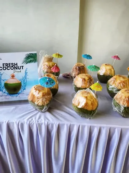 A display of fresh coconuts with straws and umbrellas, a refreshing and natural beverage choice for a Thanksgiving dinner party.