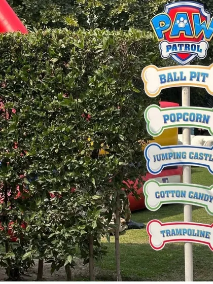 Themed signage helps guide guests to all the fun activities. This Paw Patrol signpost points the way to the ball pit, popcorn, jumping castle, cotton candy, and trampoline, building excitement for the little pups.