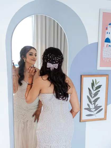 The bride takes a final look in the mirror, a quiet moment of reflection before heading to her ceremony. The unique arch-shaped mirror adds an artistic touch to this bridal portrait.
