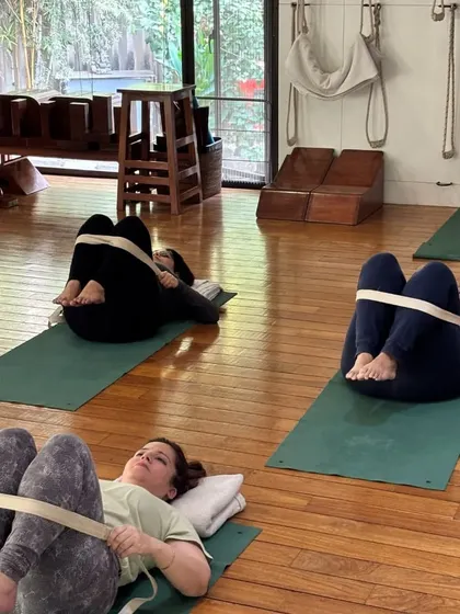 Students in a restorative pose, using belts to support their legs. This allows for a deep release of tension in the hips and lower back.