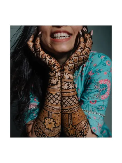 A close-up of the bride's beautiful and intricate Mehendi design. The focus is on the artistry of the henna, a key part of the bridal look.