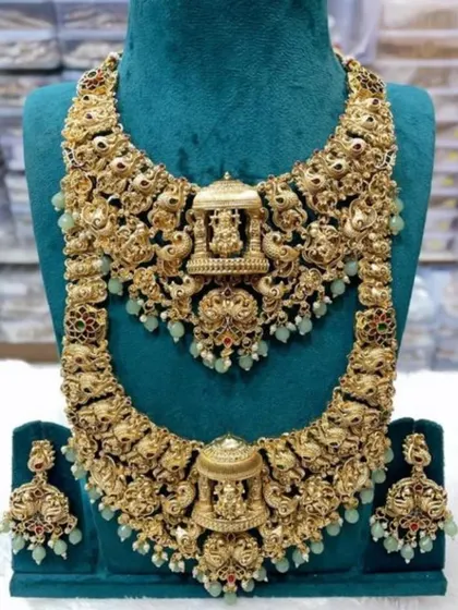 A detailed view of one of my most requested temple jewellery sets. This antique gold-plated double necklace set features intricate carvings of deities and peacocks, complete with matching jhumkas, perfect for a traditional South Indian or royal-themed wedding.