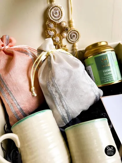 The 'Bandhan' hamper includes two elegant potlis for dry fruits, a beautiful lumba rakhi set, and premium tea.