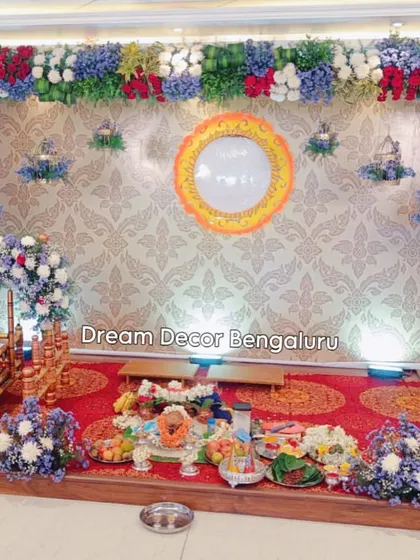 The complete setup for a naming ceremony, showing the stage, cradle, and the area for pooja items. The colorful flowers create a joyous and celebratory atmosphere.