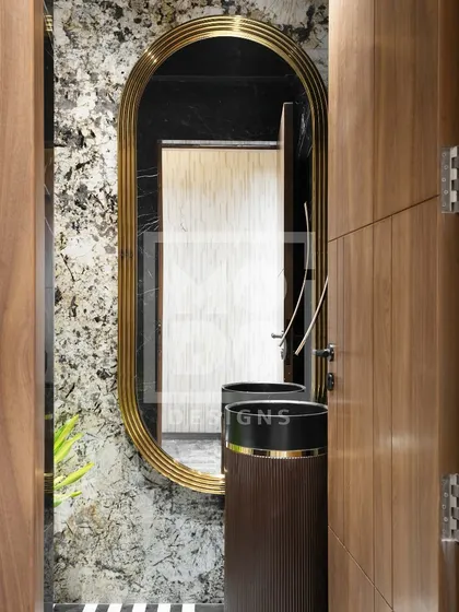 This elegant, elongated oval mirror with a thick gold frame adds a touch of vintage glamour to this powder room, complementing the dark pedestal sink and textured walls.