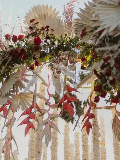 Details that define the design. The combination of exotic red heliconia, dried palms, and lush roses created a rich texture that was central to this mandap's dramatic and luxurious feel.