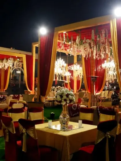 Elegant guest seating with red and gold decor under a canopy of chandeliers, perfect for a grand, open-air wedding reception.