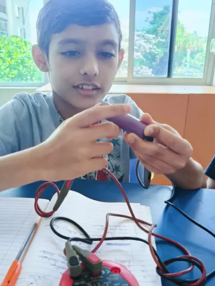 A student tests the power level of a battery before installing it in their project. This practical step reinforces their understanding of electrical energy.