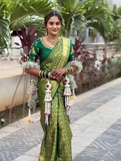 A full-length view of the bride in her green saree and our custom floral accessories. The long kalire are a standout piece of her Haldi ensemble.