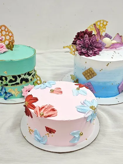 A collection of modern buttercream cakes made by a student. The class covers techniques like creating a leopard print fault line effect, watercolor blending, and palette knife painting with florals.