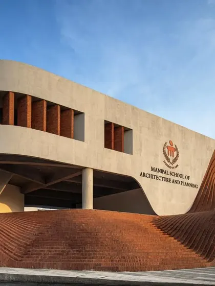 The facade of the Manipal School of Architecture and Planning features a fluid, wave-like brick structure that rises from the ground. This element serves as both an entrance and an informal amphitheater, creating a democratic space that is open and inviting.