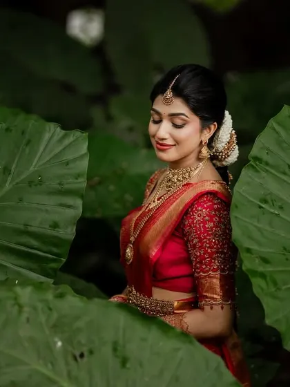 A beautiful bridal portrait framed by lush green leaves. This creative composition adds an artistic and natural touch to the image.
