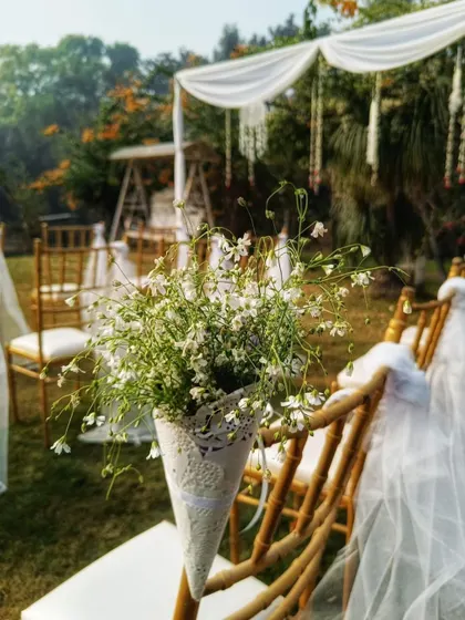 A close-up of the aisle decor. Each chair is adorned with a cone of baby's breath and a delicate tulle sash, adding a touch of sophisticated detail to the ceremony seating.