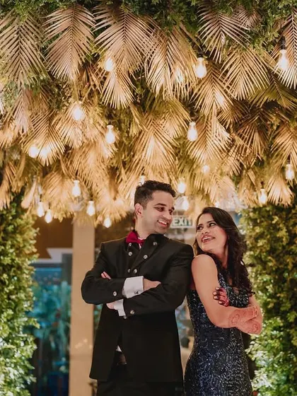 The happy couple, Rucha and Chinmay, posing under the stunning tropical-themed archway. The warm lighting and lush greenery created a perfect photo opportunity.