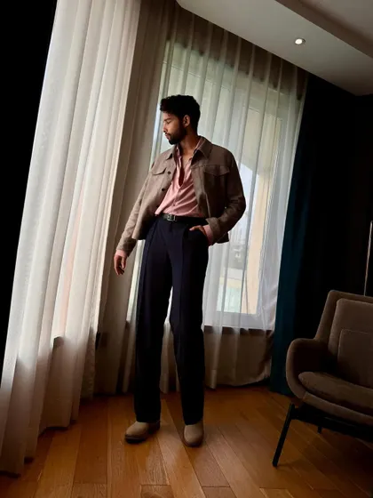 A more contemplative shot of Siddhant. The natural light highlights the soft textures and colors of the outfit.