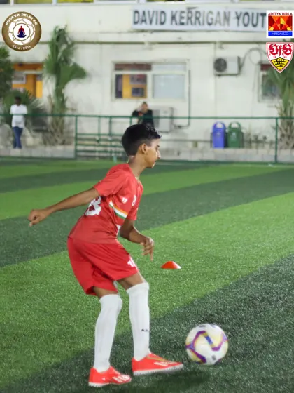 A young player in full concentration, maneuvering the ball during a drill. This focus is what we instill in our players. It's about being present and giving 100% in every moment of training.