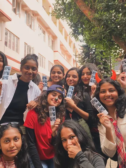 A big group of friends posing together with their photo strips after a fun session in the booth.