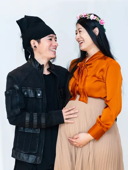 A happy, interactive moment in the studio. The clean white background ensures that the couple's joyful expressions and connection are the main focus of the photograph.