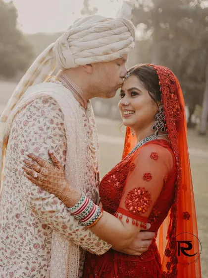 A close-up portrait filled with affection. The groom gently kisses the bride's forehead, a timeless and romantic moment captured forever.