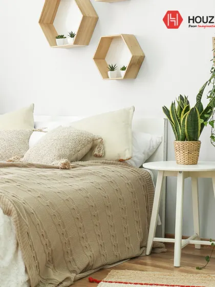 An example of biophilic design, this bedroom brings nature indoors with an abundance of plants and natural materials. The hexagonal wall shelves and knitted throw add a touch of cozy, organic style.
