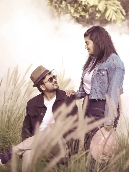 A stylish pre-wedding portrait with a rustic, natural background. The use of props like hats adds personality to the shoot.