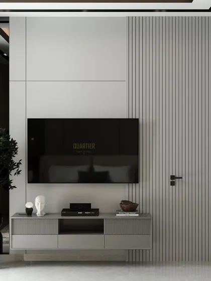 A guest bedroom design for Apex D'Rio featuring a feature wall with intricate mouldings and quilting, accented with gold strips. The TV unit on the opposite wall has a door flushed into the paneling for a seamless look.