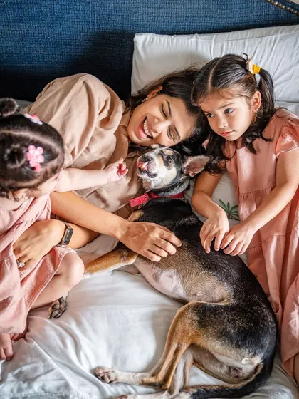 A pile of love! A mom and her two daughters cuddle in bed with their sweet rescue dog, Choco.