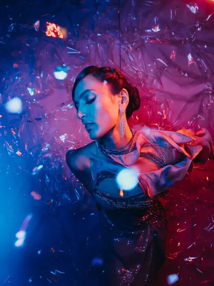 A model poses against the tinted cellophane backdrop, with light creating a dynamic and edgy effect, perfect for an unconventional party.
