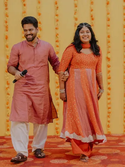 The happy couple makes their entrance at their pre-wedding function. Their smiles show the joy and excitement of the celebrations to come.