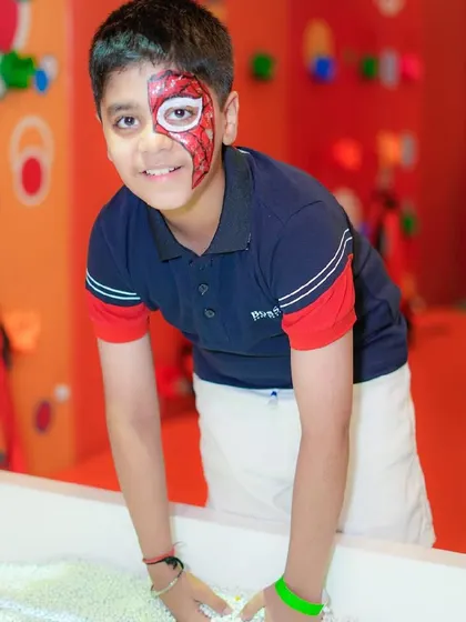 A boy smiles for the camera, showing off his half-face Spider-Man paint.