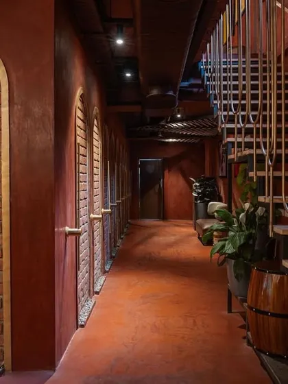 The corridor at 'Chambal' uses repetition in the arched brick doorways and the sleek staircase railing to create a strong sense of rhythm and direction, guiding patrons through the space.