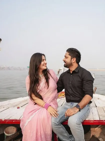 Another beautiful angle from the boat photoshoot in Banaras. This image captures the couple's happy interaction with the scenic river and birds in the background.