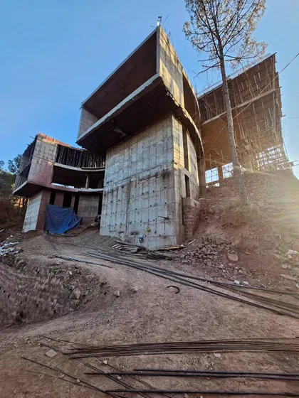 An upward-looking shot of the cantilevered structure, emphasizing its dramatic projection out from the hillside. This perspective showcases the ambitious structural design and the creation of floating architectural forms.