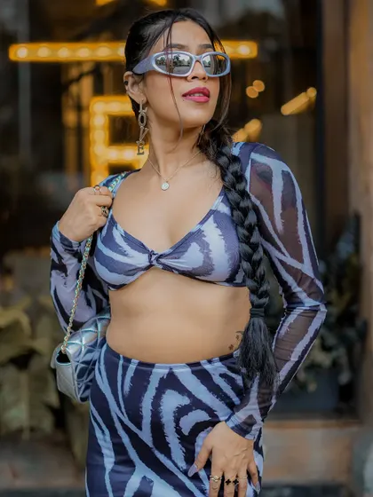A profile shot that highlights the unique sunglasses and braided hairstyle.