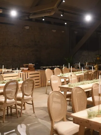 Long, rustic wooden tables set for an intimate dinner. The simple elegance of the table runners and candles created a warm and inviting atmosphere in the industrial-chic venue.