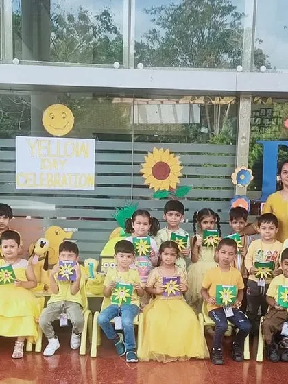 A group of students in yellow attire proudly display their star-shaped crafts, made during our Yellow Day celebration.