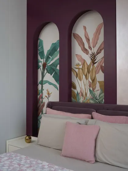 The arched niches behind the bed feature tropical wallpaper, creating a vibrant yet serene focal point in this biophilic-designed guest room.