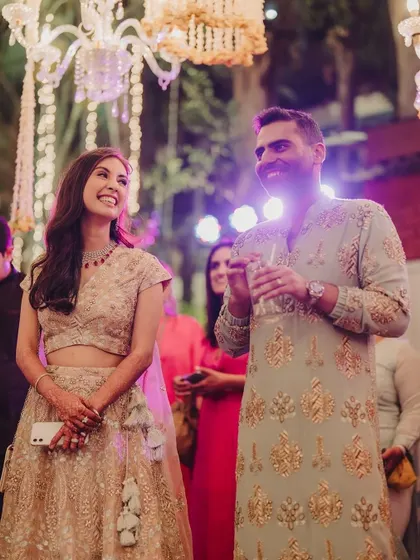 A couple enjoying their Mehendi party, sharing a happy moment under beautiful chandelier lighting.