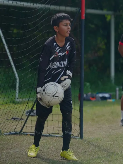 A young goalkeeper, focused and fearless, ready for action between the posts during a Delhi Youth League match.