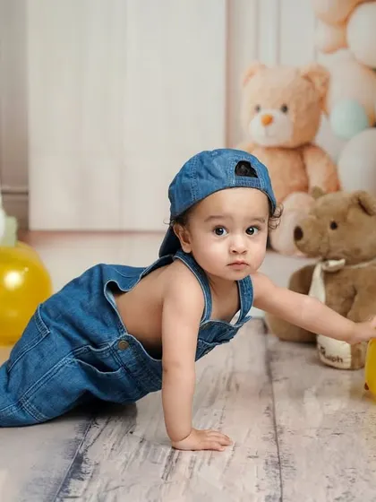 On the move! This crawling shot shows a different perspective of the birthday boy exploring his fun, themed setup with denim overalls and yellow balloons.