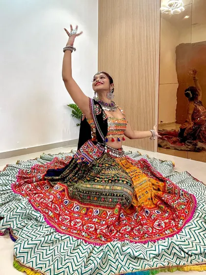 This full-circle lehenga has an amazing spread, featuring panels of different colors and patterns. It's paired with a mirror-work blouse and a full set of oxidized jewelry for a complete festive look.