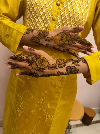 A client showing off her beautiful floral vine mehndi. The yellow outfit provides a lovely contrast.