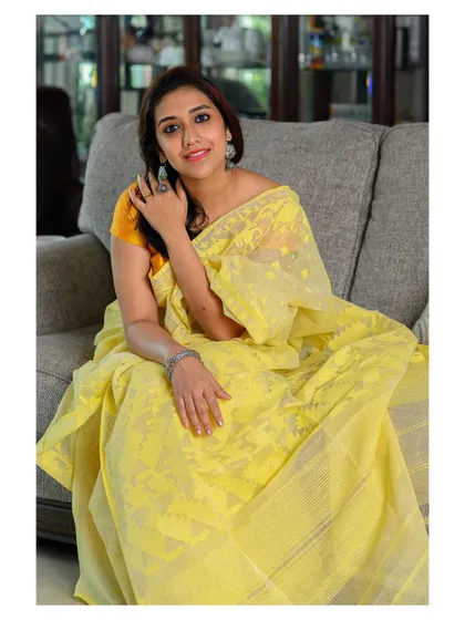 A light and airy portrait featuring a handwoven Dhakai Jamdani saree. The natural pose and home environment make this a perfect shot for a brand that emphasizes comfort and elegance.