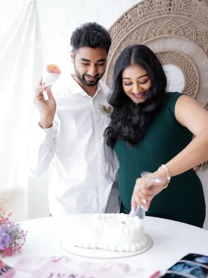 A sweet gender reveal celebration. The couple is captured cutting a cake, with pink baby clothes and a sonogram hinting at their happy news.