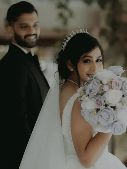 A candid shot of the bride looking back with a smile, her bouquet of pastel roses adding a touch of color.